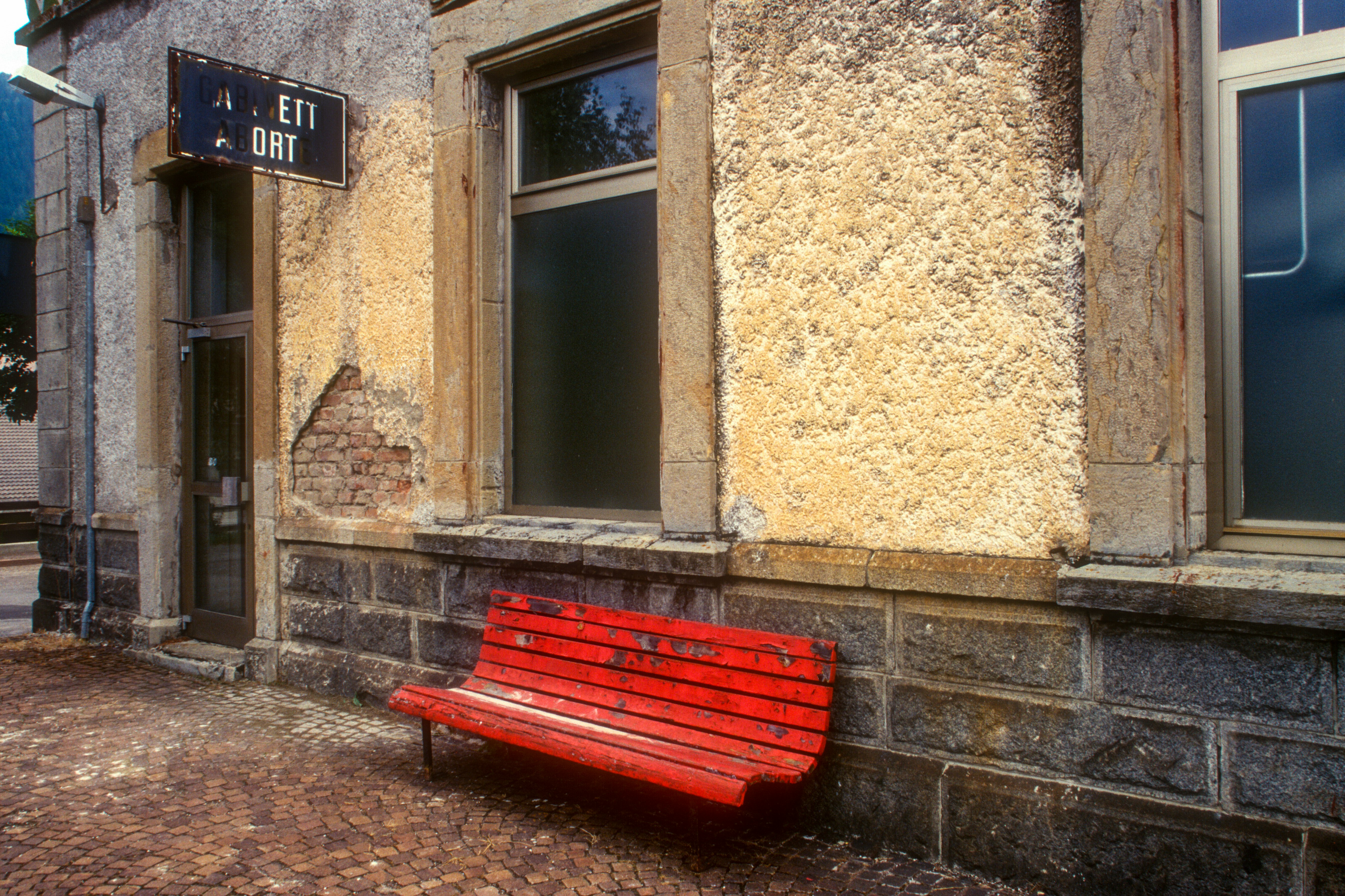 red wooden bench beside brown concrete wall